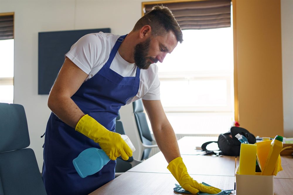Profissional de limpeza higienizando uma mesa de escritório